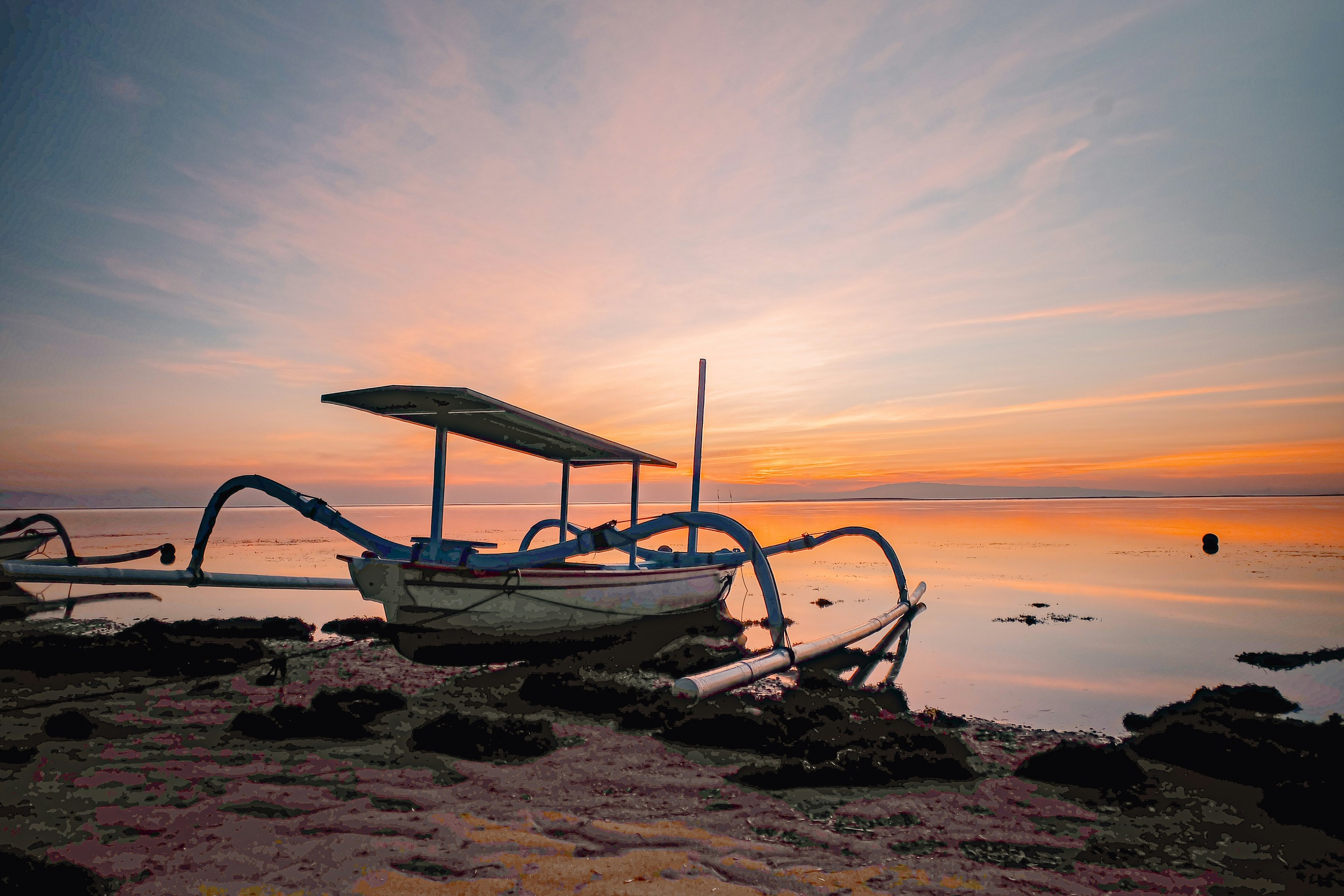 Balinese fishing boat at sunset on a calm Bali ocean
